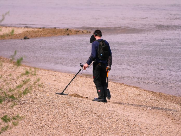 Person er på skattejagt med metal detektor